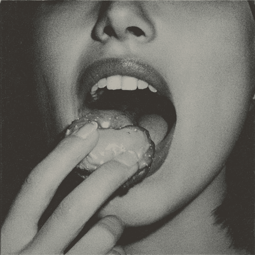Black-and-white close-up photograph of a mouth biting into a doughnut